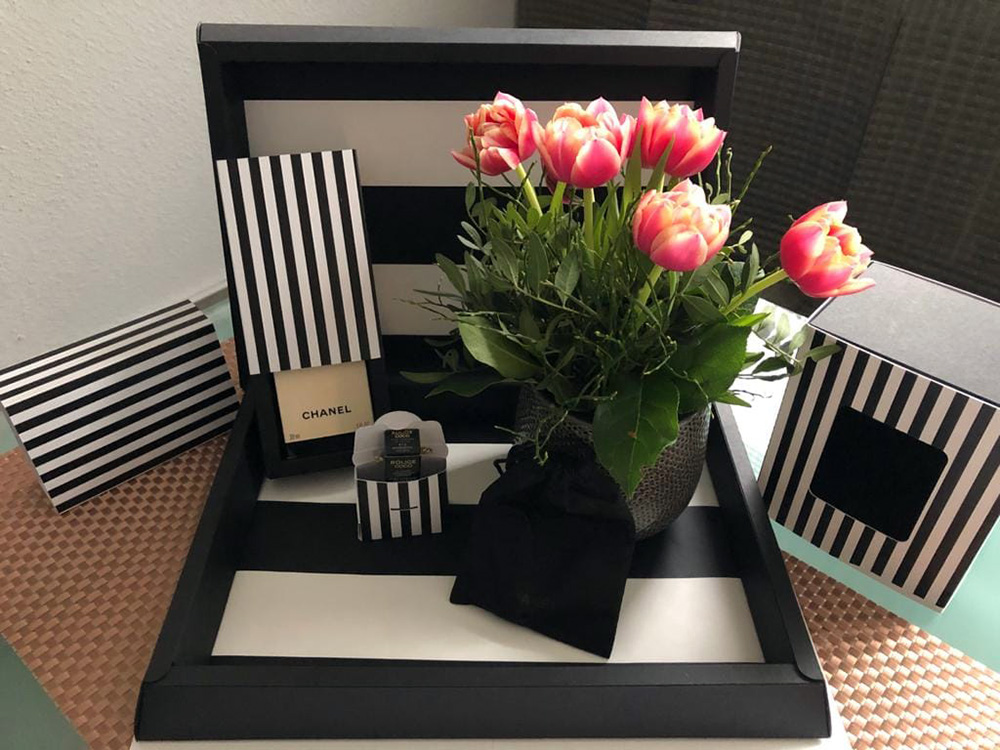 Pr&auml;sentverpackungen und Geschenkboxen mit schwarz-wei&szlig;em Streifendesign neben Blumen und Dekoartikeln