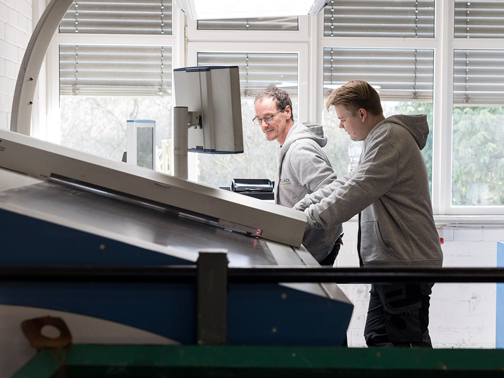 Zwei Mitarbeiter bedienen eine Produktionsmaschine in der Verpackungsfertigung von Tillack Creativ Verpackungen